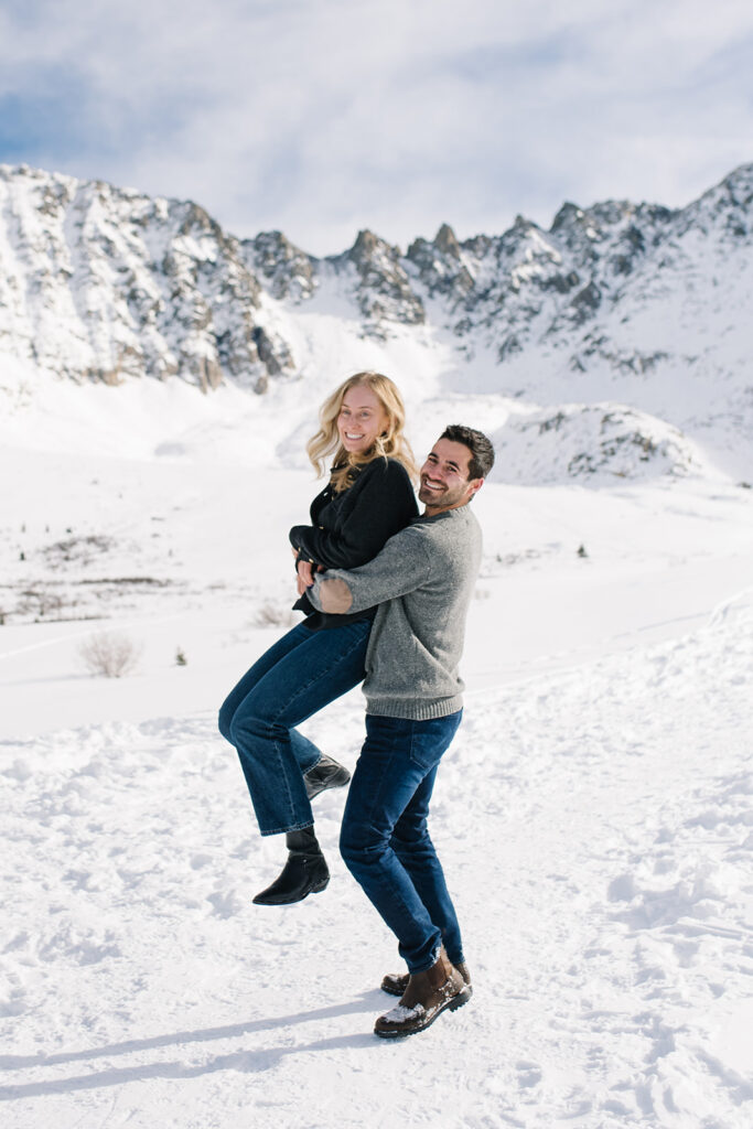 Winter engagement photos in Colorado with snow-covered mountains in the background.