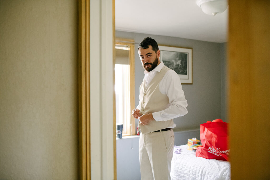 Groom buttoning his suit jacket before his wedding at Wedgewood Mountain View Ranch.