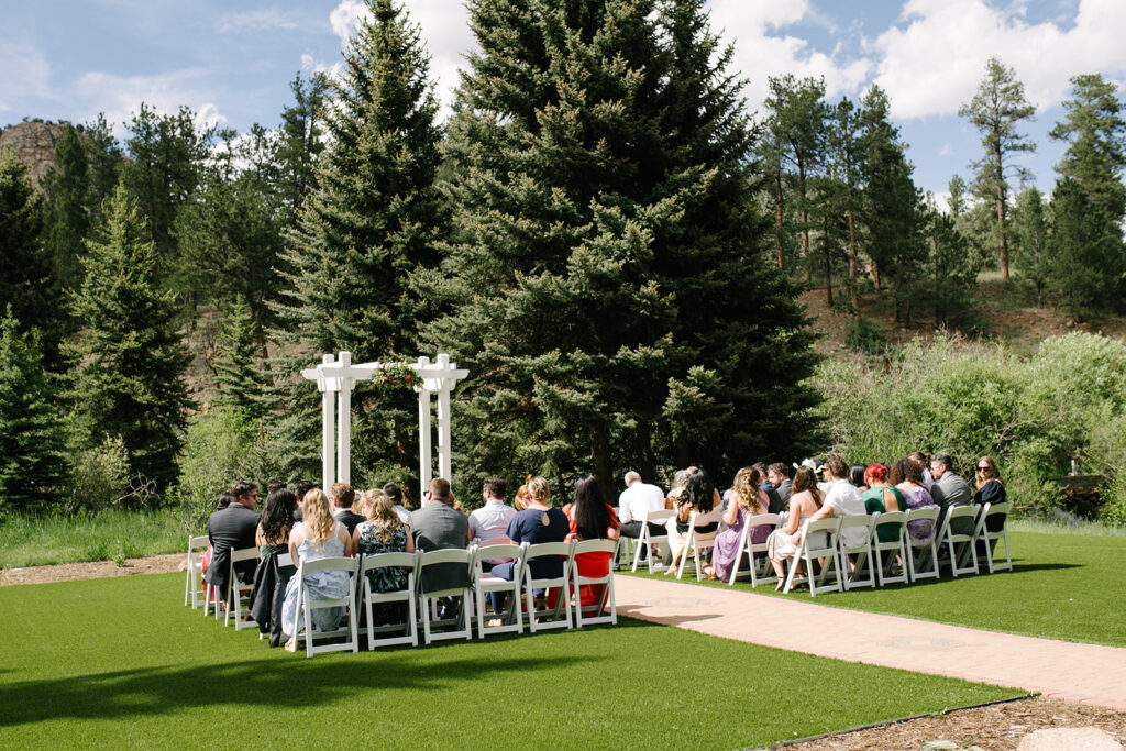 Outdoor wedding ceremony at Wedgewood Mountain View Ranch in Pine, CO with mountain views and a rustic wooden arbor.