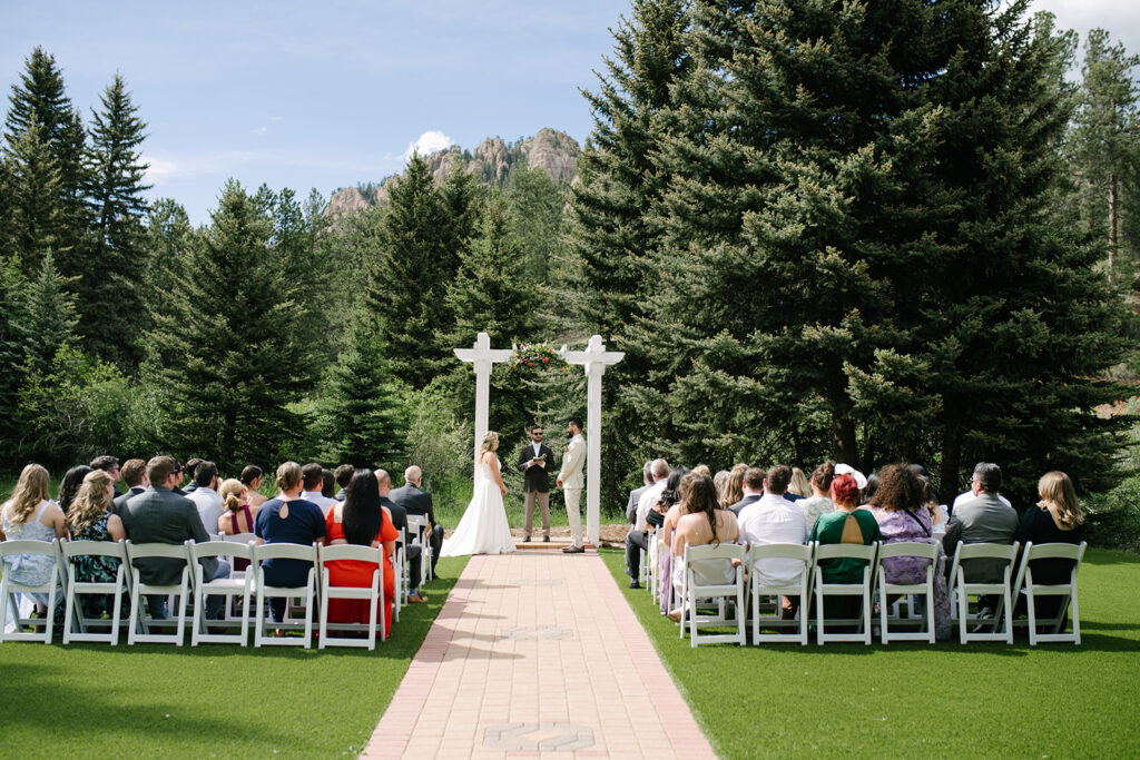 Bride and groom during their wedding ceremony at Wedgewood Mountain View Ranch, surrounded by Colorado pine trees