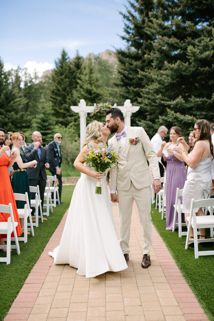 Bride and groom during their wedding ceremony at Wedgewood Mountain View Ranch, surrounded by Colorado pine trees