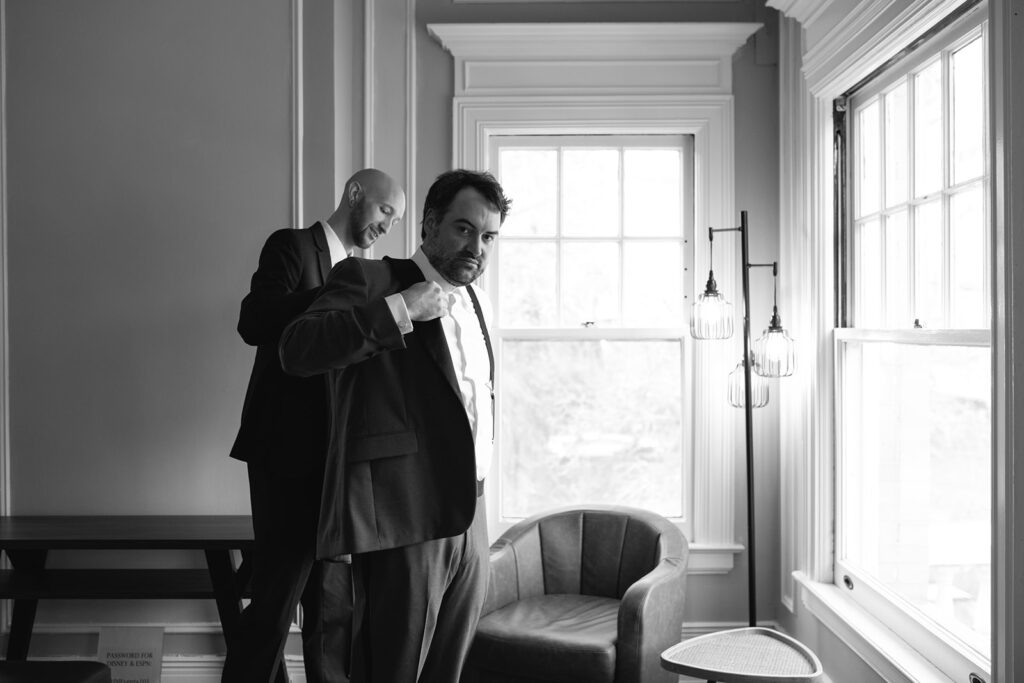 Groom tying tie in upstairs room of Grant Humphreys Mansion before wedding ceremony
