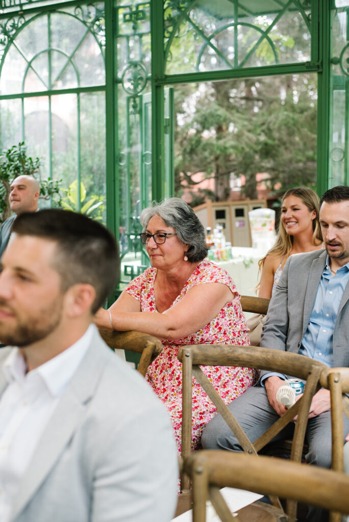 intimate and candid moments of guests at a ceremony taking place at the Mosaic Solarium in the Denver Botanic Gardens